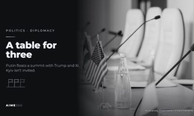 National flags and microphones on a conference table, in black and white, beside the headline A table for three