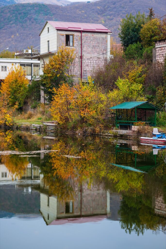Autumn trees and a house reflected in a lake in Vanadzor